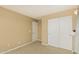Empty bedroom with tan walls and white closet doors and trim at 21610 N Bradford Dr, Maricopa, AZ 85138
