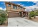 Front elevation featuring a two-story home with a two-car garage, covered porch, and xeriscaped yard at 21610 N Bradford Dr, Maricopa, AZ 85138