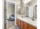Bright bathroom featuring dual sinks, tile countertop, and a view into an adjacent bedroom, creating an open feel at 26409 N 49Th Ln, Phoenix, AZ 85083