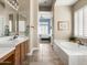 Bright bathroom features dual sinks, soaking tub, and tiled floors leading to a light-filled bedroom at 26409 N 49Th Ln, Phoenix, AZ 85083