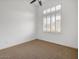 Minimalist bedroom with neutral carpet, white walls, ceiling fan, and a bright window offering natural light at 26409 N 49Th Ln, Phoenix, AZ 85083