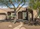 Inviting desert home with a tile roof and arched entryway surrounded by mature landscaping at 26409 N 49Th Ln, Phoenix, AZ 85083