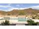A swimming pool with waterfall features are set against a backdrop of a mountain and a bright blue sky at 26409 N 49Th Ln, Phoenix, AZ 85083
