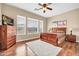 A comfortable bedroom with a ceiling fan, wood floors, soft carpet, and three large windows at 2959 W Eastman Dr, Anthem, AZ 85086