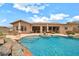 Backyard pool with rock features, outdoor kitchen, covered patio and blue skies at 2959 W Eastman Dr, Anthem, AZ 85086