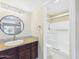 Bathroom with granite vanity, wood cabinet, round mirror, and glass shower doors at 3500 N Hayden Rd # 206, Scottsdale, AZ 85251