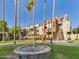 Exterior view of a lush community courtyard with mature palm trees, green grass, and a water fountain at 3500 N Hayden Rd # 206, Scottsdale, AZ 85251