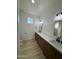 Modern bathroom with dual sinks, wood cabinets, quartz counters, and a large window at 3627 W Palmaire Ave, Phoenix, AZ 85051