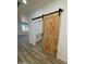 Bedroom with wood-look flooring and a rustic barn door leading to an ensuite bathroom at 3627 W Palmaire Ave, Phoenix, AZ 85051