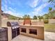 Covered outdoor kitchen features a Weber grill, countertop, and built in shelving for outdoor entertaining at 5812 W Spur Dr, Phoenix, AZ 85083