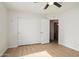 Bedroom featuring light laminate floors, a closet, a ceiling fan, and easy access to the bathroom at 6366 W Saint John Ave, Glendale, AZ 85308