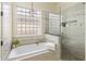 A luxurious bathroom featuring a soaking tub, a glass-enclosed shower, and decorative tile work at 654 E County Down Dr, Chandler, AZ 85249