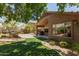 Backyard featuring well-manicured green grass, gravel landscaping, and a covered patio at 7456 W Irma Ln, Glendale, AZ 85308