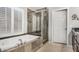 Bathroom featuring a soaking tub, glass enclosed shower and tiled walls at 7456 W Irma Ln, Glendale, AZ 85308
