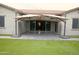 Inviting back patio with dual shade umbrellas, tiled floor, artificial turf, and sliding glass doors to the home's interior at 9187 W Parkside Ln, Peoria, AZ 85383