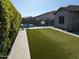 Lush backyard featuring artificial turf, pool with slide, and privacy hedging at 9187 W Parkside Ln, Peoria, AZ 85383