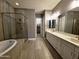 Modern bathroom with a glass-enclosed shower, soaking tub, and double vanity sinks at 9187 W Parkside Ln, Peoria, AZ 85383