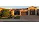 Inviting home exterior with a stone facade, manicured lawn, and a spacious three-car garage at 9187 W Parkside Ln, Peoria, AZ 85383