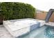Close-up of a sparkling hot tub with a tile surround and backdrop of a mature privacy hedge at 9187 W Parkside Ln, Peoria, AZ 85383