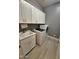 Laundry room with white cabinets, sink, gray walls, modern washer and dryer, and tile floors at 9187 W Parkside Ln, Peoria, AZ 85383