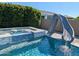 Beautiful in-ground pool with a hot tub, a slide, a stone surround, and a privacy hedge at 9187 W Parkside Ln, Peoria, AZ 85383