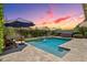 Backyard with a sparkling pool, hot tub, and lush landscaping, illuminated by string lights at 1057 W Laurel Ave, Gilbert, AZ 85233