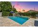 Backyard featuring a sparkling pool, hot tub, and lush landscaping, illuminated by string lights at 1057 W Laurel Ave, Gilbert, AZ 85233