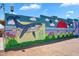 A colorful mural featuring a whale, flowers, and people holding flowers on a community building wall at 1306 E Fillmore St, Phoenix, AZ 85006