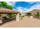 Expansive brick paved backyard featuring a covered carport with lush landscaping under a bright blue cloudy sky at 13204 W Palo Verde Dr, Litchfield Park, AZ 85340
