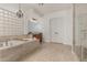 Elegant bathroom with a soaking tub, glass block window, chandelier, and a glass-enclosed shower at 13204 W Palo Verde Dr, Litchfield Park, AZ 85340