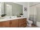 Well-lit bathroom featuring a wooden vanity and a neutral-striped shower curtain at 13204 W Palo Verde Dr, Litchfield Park, AZ 85340