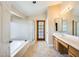 Well-lit bathroom with a soaking tub, glass shower, and wood vanity at 13650 N 70Th Dr, Peoria, AZ 85381