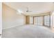 Spacious living room featuring plantation shutters, a ceiling fan, and neutral carpeting at 13650 N 70Th Dr, Peoria, AZ 85381