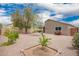Spacious backyard featuring a desert landscape, mature tree, gravel, and a patio set with chairs at 16031 W Williams St, Goodyear, AZ 85338