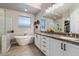 Bright bathroom featuring double sinks, a soaking tub, a glass shower and a walk-in closet at 16226 S 35Th Dr, Phoenix, AZ 85045