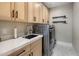 Well-lit laundry room boasts modern cabinets, a sink, countertops, and laundry appliances at 20055 N 96Th Way, Scottsdale, AZ 85255