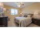 A warmly decorated bedroom features a ceiling fan, a comfortable bed with decorative pillows, and matching bedside lamps at 21841 N Ingram Ct, Maricopa, AZ 85138