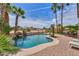 Resort style backyard pool with lush tropical landscaping, a rock waterfall, and a beautiful stone patio at 21841 N Ingram Ct, Maricopa, AZ 85138