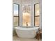 Bright luxury bathroom featuring a free-standing soaking tub under a modern light fixture at 24645 N 117Th St, Scottsdale, AZ 85255