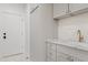 Bright laundry room features white cabinets, stone countertops, and modern faucet with storage at 24645 N 117Th St, Scottsdale, AZ 85255