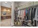 Walk-in closet showing built-in storage shelves and hanging rods; view of bathroom at 25971 W Taro Dr, Buckeye, AZ 85396