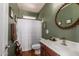 Bathroom with green walls featuring a single sink vanity, a toilet, and a shower with a white curtain at 3441 S Halsted Pl, Chandler, AZ 85286