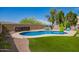 Backyard oasis featuring a sparkling pool, lush artificial grass, and desert landscaping at 3960 W Salter Dr, Glendale, AZ 85308