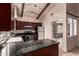 Features dark cabinetry, stainless appliances, granite counters, and vaulted ceilings with wood beams at 4420 E Covina St, Mesa, AZ 85205