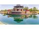 Reflective view of the Layton Lakes community sign set within a stone wall and manicured landscaping near the water at 652 E Rojo Way, Gilbert, AZ 85297