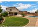 This backyard features a pool, a lawn, and a covered patio with a desert landscape at 6637 W Watkins St, Phoenix, AZ 85043