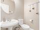 Clean half bathroom featuring a round mirror, vanity sink, and a neutral color scheme at 6847 S 27Th Pl, Phoenix, AZ 85042