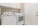 Well-lit laundry room features a modern washer and dryer set, complemented by ample upper cabinet storage at 6847 S 27Th Pl, Phoenix, AZ 85042