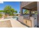 Outdoor kitchen with stainless steel grill and bar near pool area in the backyard at 6847 S 27Th Pl, Phoenix, AZ 85042