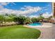 Beautiful backyard showcasing a well-kept lawn, pool with waterfall, and landscaped garden for serene outdoor enjoyment at 6971 W El Cortez Pl, Peoria, AZ 85383